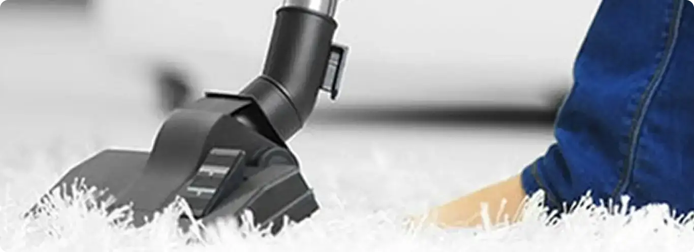 Close-up of a professional vacuuming a white carpet in Tonawanda.